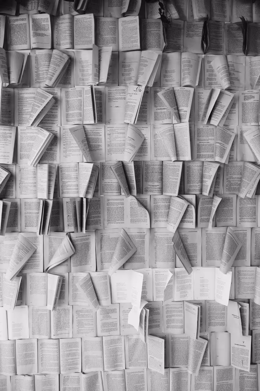 Eine ganze Wand aus dicht nebeneinander aufgeschlagenen Büchern.